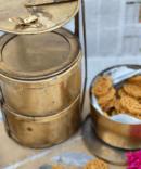 a brass material tiffin box having some snacks-Athepoo